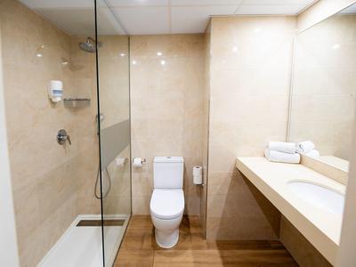 Modernes Badezimmer mit Walk-in-Dusche, WC und Waschtisch mit Handtüchern.