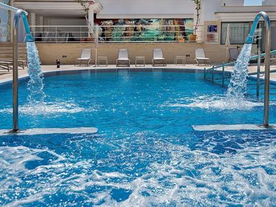 Innenpool mit Wasserfontänen und Liegestühlen im Hintergrund