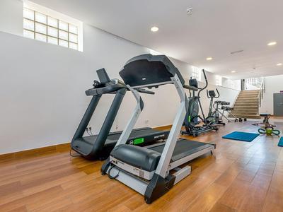 Světelná posilovna s běžeckými pásy a rotopedy na dřevěné podlaze