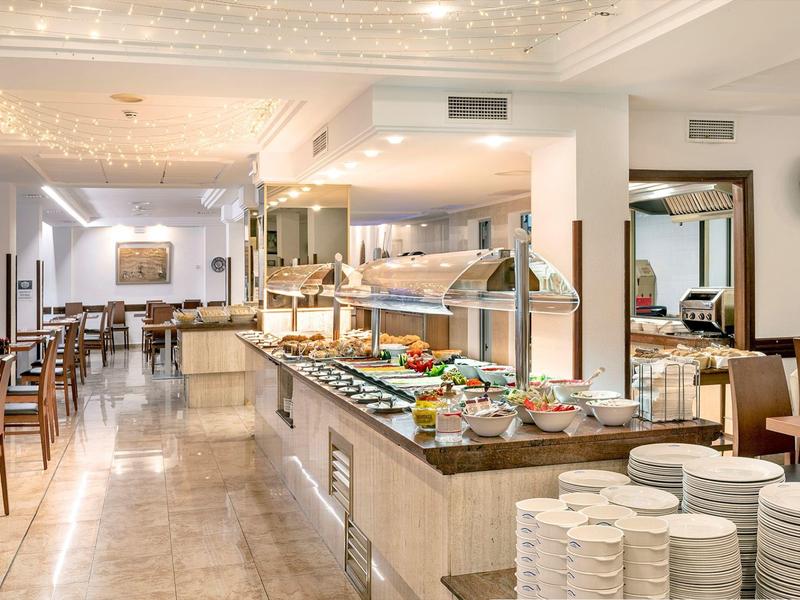 Buffetbereich in einem hellen Restaurant mit verschiedenen Speisen und gedeckten Tischen.