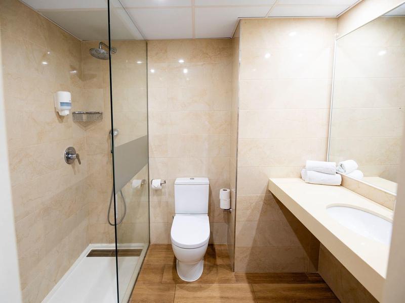 Modernes Badezimmer mit Walk-in-Dusche, WC und Waschtisch mit Handtüchern.