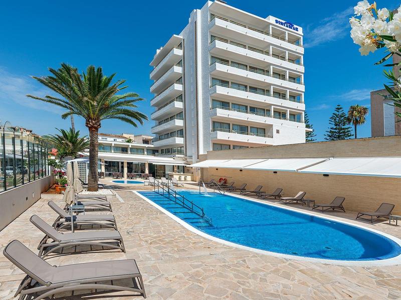 Moderner Hotelpool mit Liegestühlen und Palmen an einem sonnigen Tag