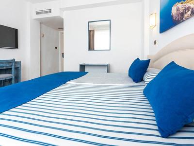 Modernes Schlafzimmer mit blau-weiß gestreiftem Bett und blauer Deko in einem hellen Raum.