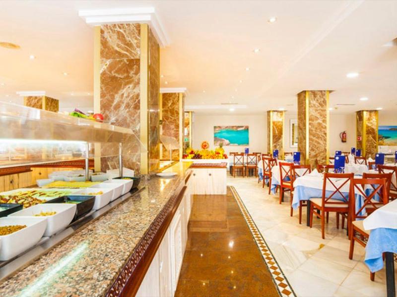 Eleganter Speisesaal mit weißen Tischen, blauen Gläsern und einem Buffet mit frischem Essen.