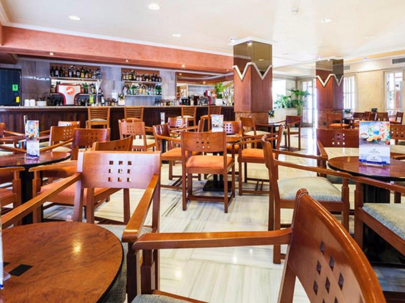 Helles Restaurant mit Holztischen, Stühlen und einem großen Buffetbereich im Hintergrund.