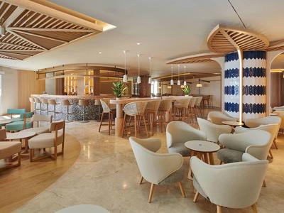 Moderne hotel lounge met gebogen bar, gestoffeerde stoelen en een warm kleurenpalet.