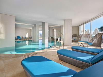 Overdekt zwembad met grote ramen en blauwe ligbedden in een modern hotel.