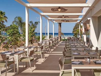 Taras hotelowy z zastawionymi stołami i widokiem na morze w tle