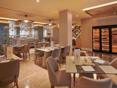 Elegantní hotelová lounge s stolky, židlemi a teplou, dobře osvětlenou útulnou atmosférou.