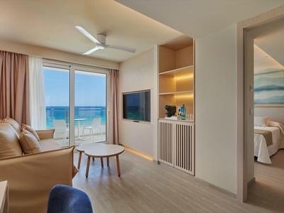 Moderne hotelkamer met woonkamer, tv, balkon en zeezicht.