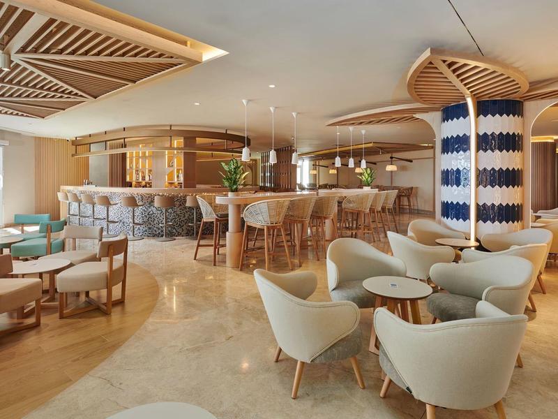 Moderne hotel lounge met gebogen bar, gestoffeerde stoelen en een warm kleurenpalet.