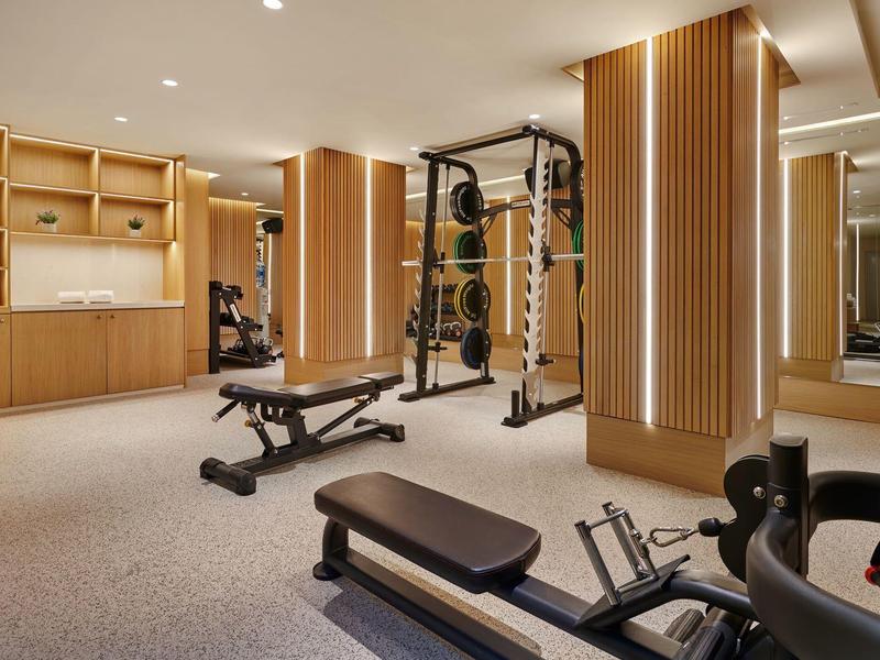 Modern fitnessruimte met gewichthefapparatuur en houten accenten in een hotel wellnessruimte.