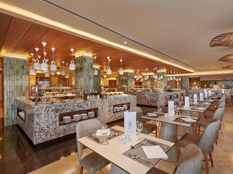 Elegant hotelrestaurant met marmeren buffetbalies en keurig opgestelde tafels en stoelen.