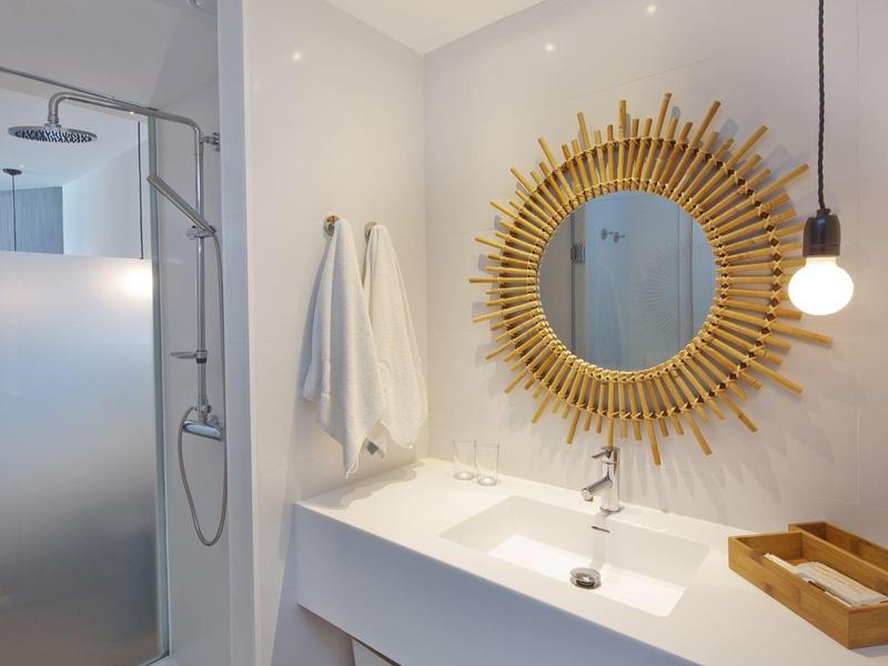 Moderne badkamer met ronde spiegel, wastafel en inloopdouche.