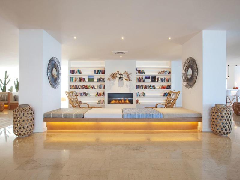 Lichte hotelhal met gezellige bank, boekenplanken en warme sfeer.