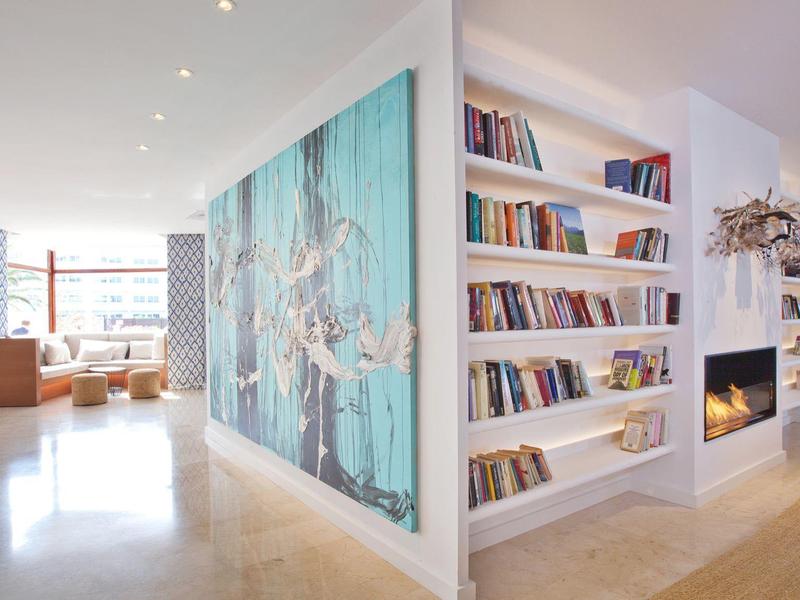 Lichte moderne hotellobby met boekenplank, open haard en zithoek.