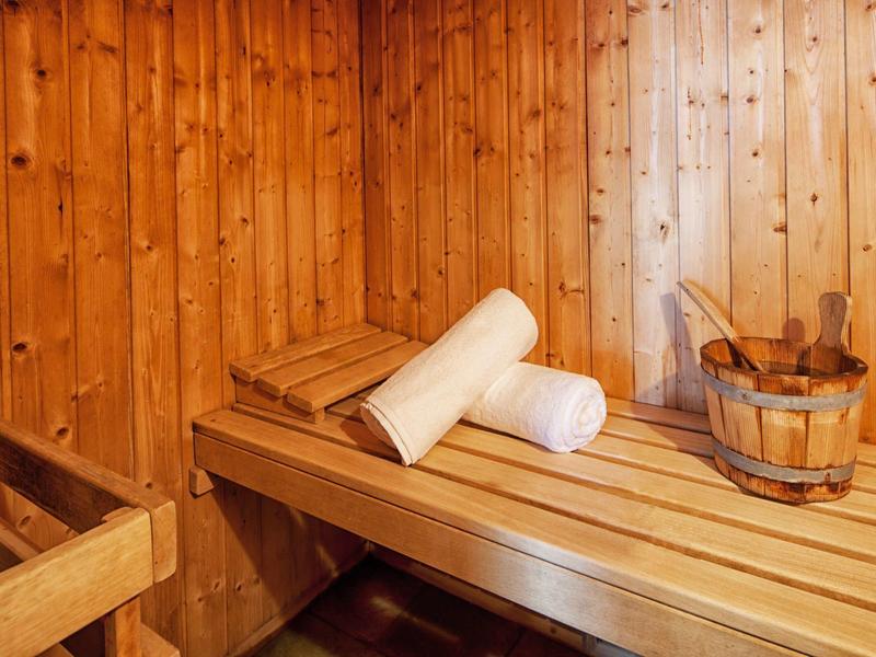 Houten sauna met handdoeken en houten emmer op de bank.