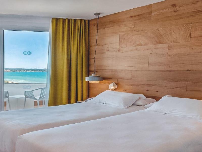 Moderne hotelkamer met twee bedden en zeezicht door grote ramen.