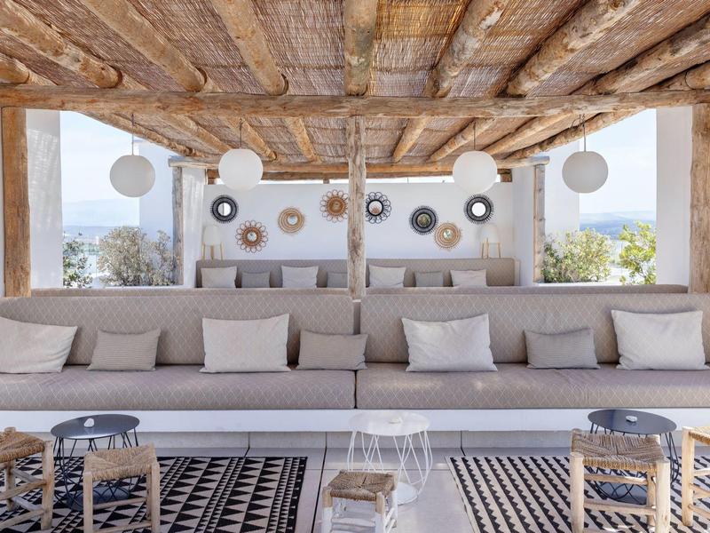 Gezellige lounge met lange banken, kussens en houten plafond in een lichte ruimte met uitzicht.