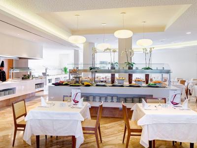 Restaurante moderno y luminoso con mesas blancas y sillas de madera en un hotel.