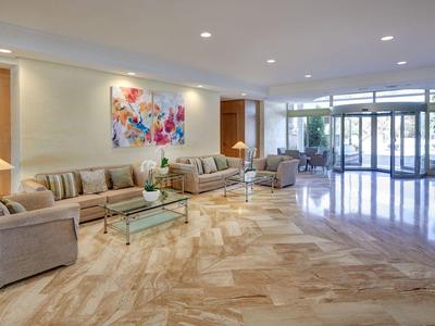 Lobby de hotel luminosa con suelo de mármol, sofás cómodos y pintura colorida en la pared.