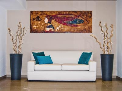 Espace de vie moderne avec canapé blanc, coussins bleus et art mural abstrait.