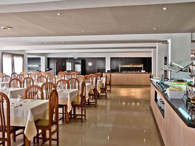 Grande salle à manger d'hôtel avec tables dressées et une zone buffet.
