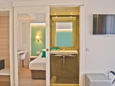 Chambre d'hôtel moderne avec lit double, salle de bain attenante et télévision murale