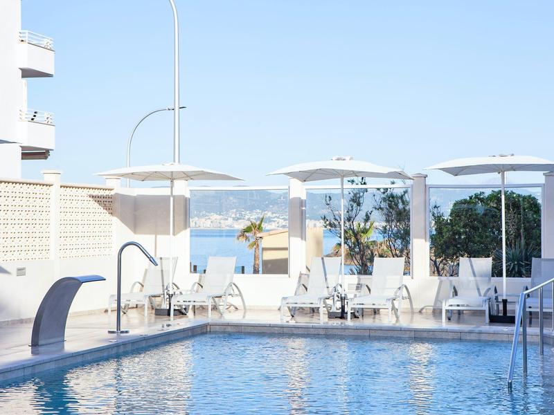 Piscine moderne avec parasols blancs et chaises avec vue sur la mer.