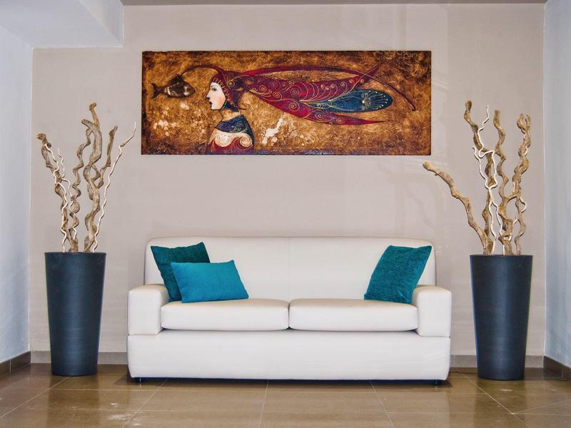 Espace de vie moderne avec canapé blanc, coussins bleus et art mural abstrait.