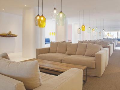 Bright, modern lounge area with beige sofas and hanging colorful lamps in a hotel.
