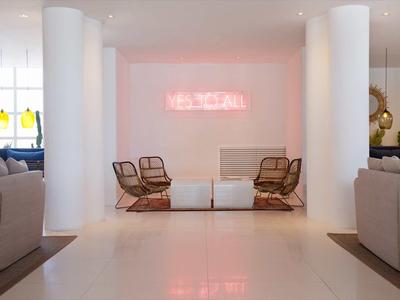 Modern hotel lounge area with chairs, sofas, and pink neon light on the wall.