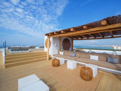 Modern outdoor seating area with pergola under blue sky by the water