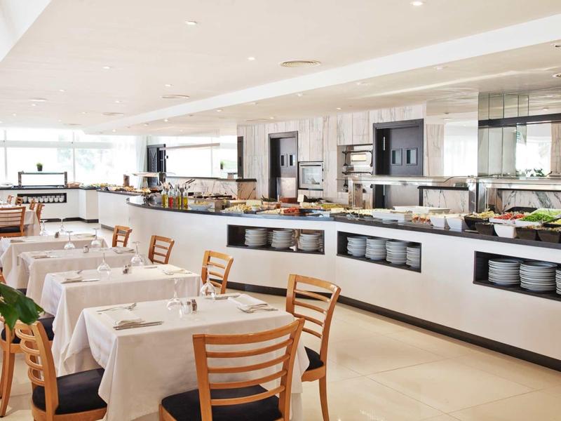 Bright modern restaurant with white tablecloths and wooden furniture in a hotel.