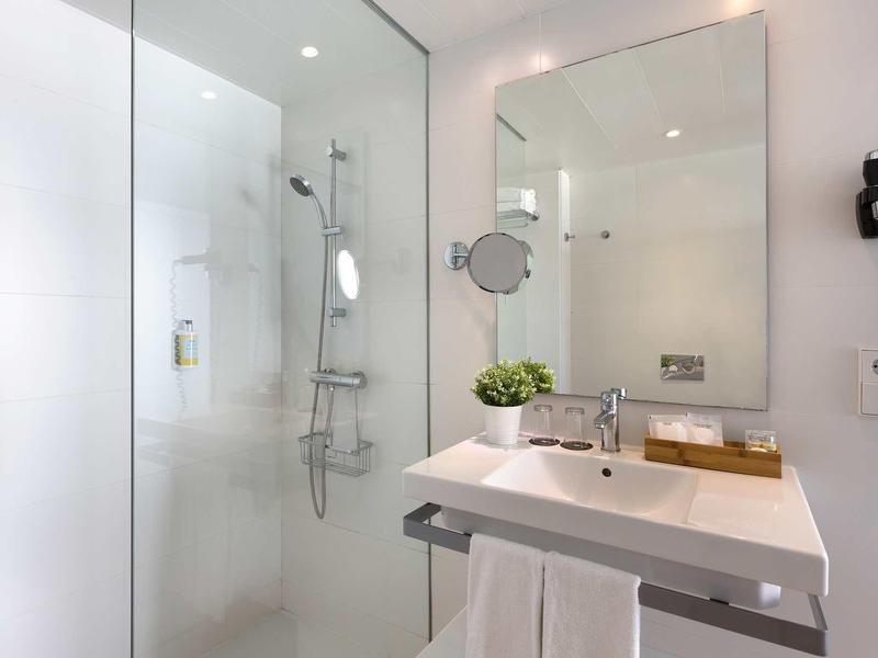 Modern bathroom with glass shower, large mirror, and white sink.