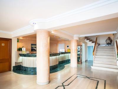 Hotel lobby met marmeren pilaren, receptiebalie en trap naar boven.