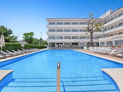 Piscina esterna blu con lettini in un hotel moderno.