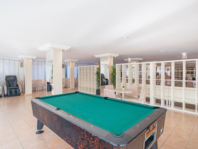 Ruime kamer met een pooltafel, witte scheidingswanden, massagestoelen en tegelvloer.