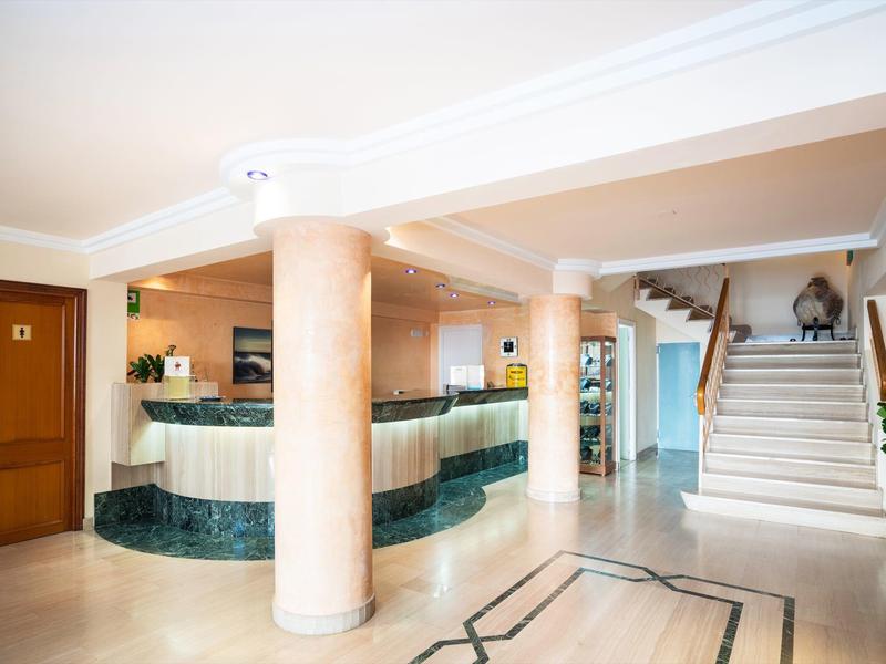 Hotel lobby met marmeren pilaren, receptiebalie en trap naar boven.