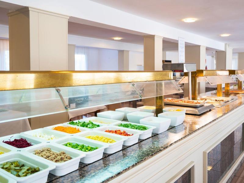 Een schoon buffet met schalen vol kleurrijke verse groenten en salade-ingrediënten in een lichte ruimte.