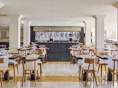 Bright hotel restaurant with wooden chairs and tables arranged neatly.