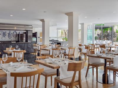 Jasna nowoczesna restauracja z drewnianymi stołami i krzesłami, nakryta szkłem i sztućcami.