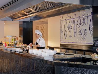 Hotel reception with a staff member behind a black marble counter and decorative display.