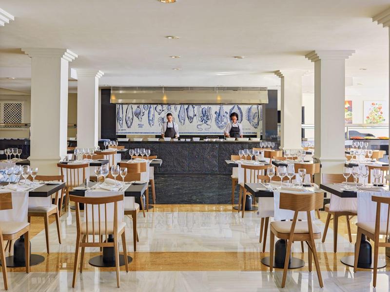 Bright hotel restaurant with wooden chairs and tables arranged neatly.
