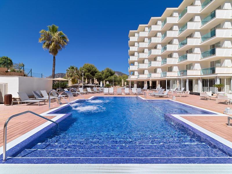 Outdoor hotel pool with sun loungers and palm trees on a sunny day