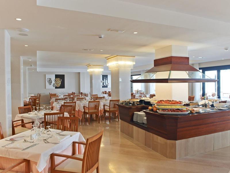 Lichte hotel eetkamer met buffet en gedekte tafels.