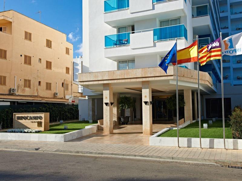 Modern hotel met ingang en vlaggen onder een heldere blauwe lucht.