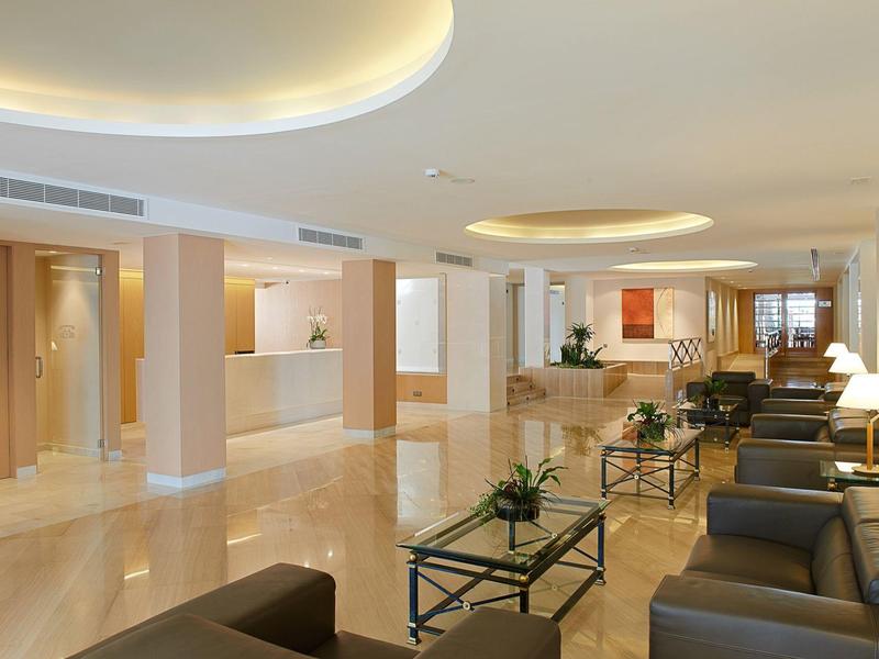 Lichte hotellobby met leren stoelen, glazen koffietafels en planten.