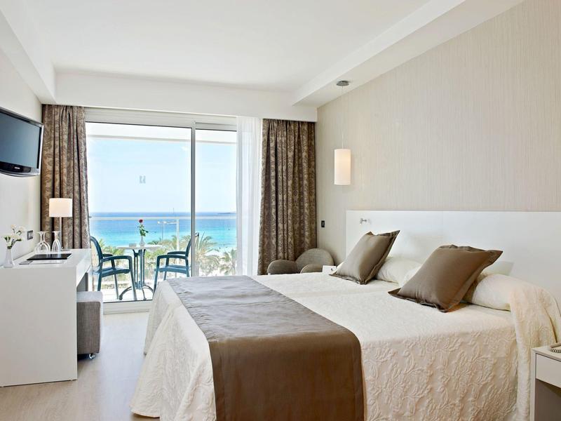 Modern hotelkamer met uitzicht op zee en balkon met zitgelegenheid.