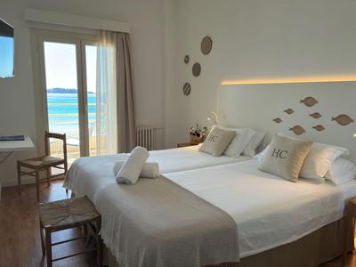 Lichte hotelkamer met twee bedden en zeezicht door grote ramen en balkon